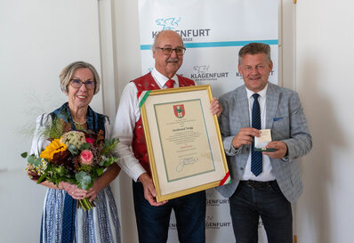 Ferdi Tengg bekam von Bürgermeister Christian Scheider der  Ehrpfennig der Landeshauptstadt Klagenfurt verliehen. Seine Gattin bekam  einen Blumenstrauß geschenkt.  Foto: StadtKommunikation/Wiedergut