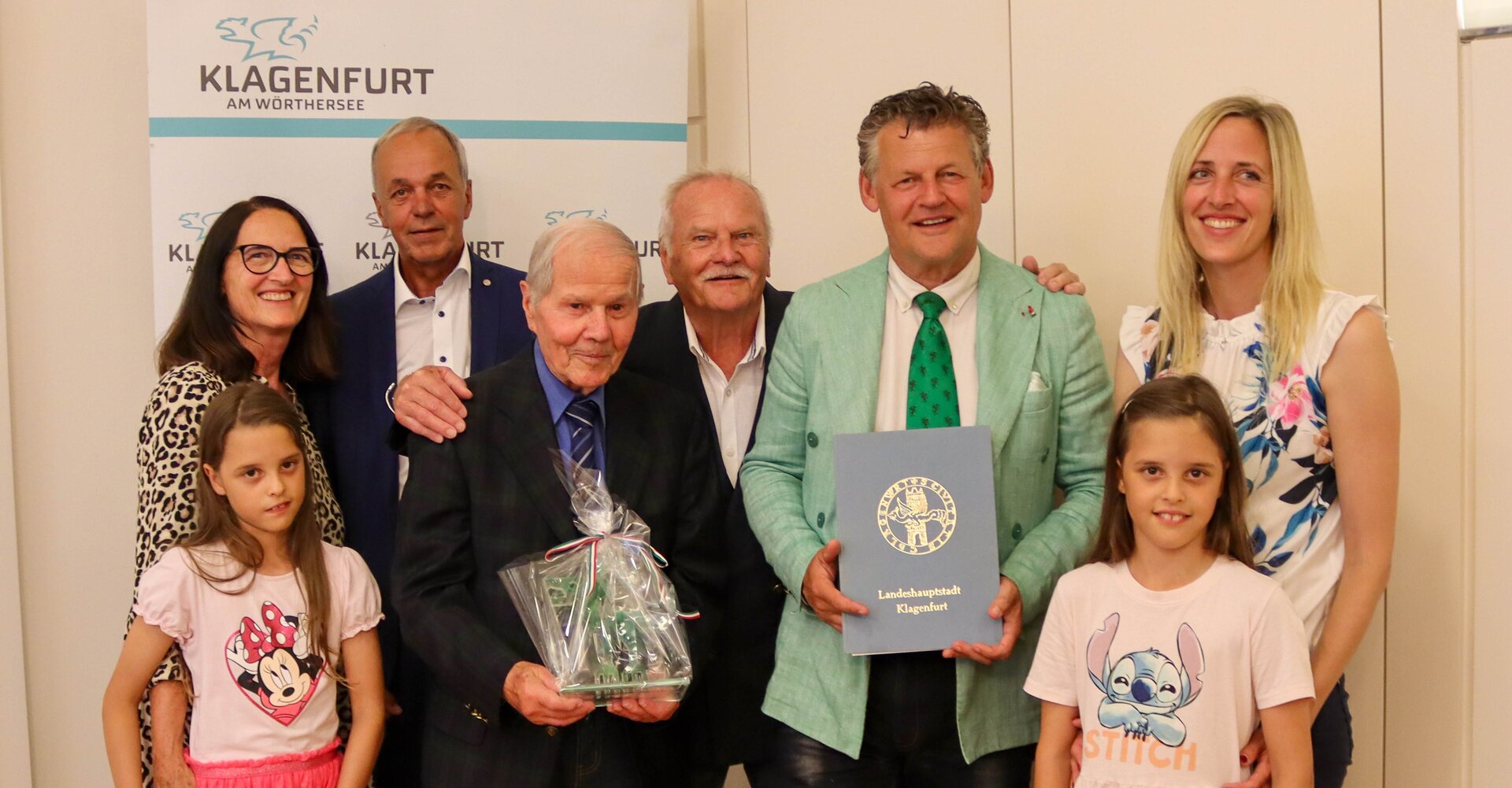 Bürgermeister Christian Scheider überreichte Direktor Oberschulrat Horst Jellitsch den Gläsernen Lindwurm der Landeshauptstadt. Bruder, Sohn, Schwiegertochter, Enkelin und die beiden Urenkelinnen waren bei der Ehrung mit dabei. Foto: StadtKommunikation/Tilli