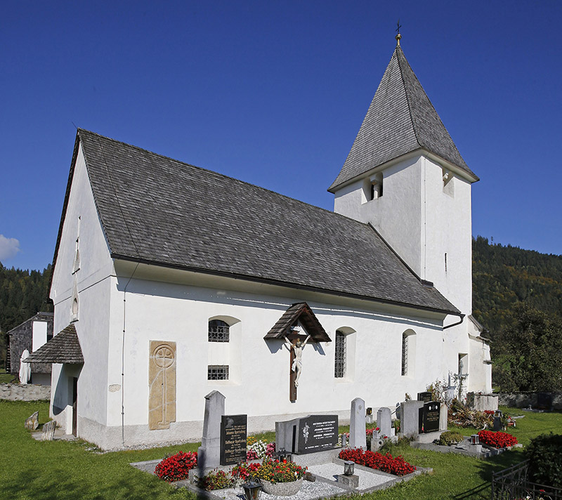 Kirche St. Peter am Bichl mit großem Kreuz an der Seitenwand, Gräber mit Blumen im Vordergrund©StadtPresse/Eggenberger