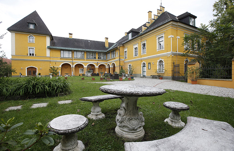Das Schloss St. Georgen mit gelber Fassade, Garten, im Vordergrund Steintisch und steinerne Hocker©StadtPresse/Eggenberger