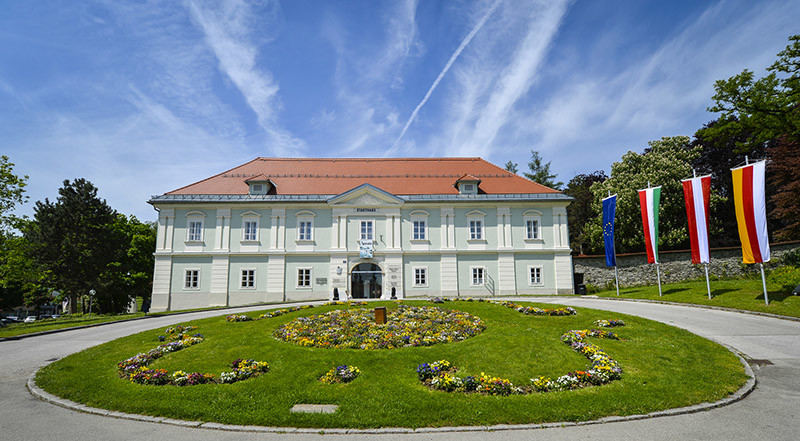 Das Stadthaus auf einem kleinen Hügel davor ein blühendes Rondeau in der Mitte der Auffahrt©StadtPresse/Helge_Bauer