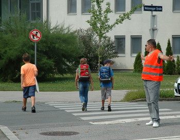 Schülerlotse hilft Kindern beim Queren der Straße