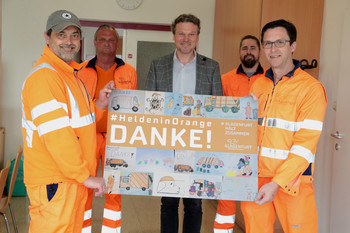 Entsorgungsreferent Vzbgm. Wolfgang Germ und Mitarbeiter der Entsorgung präsentieren die besten Kinderzeichnungen der Aktion „Helden in Orange“. Foto: StadtPresse/Wajand