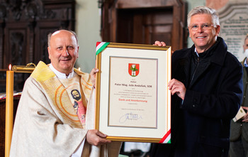Vizebürgermeister Prof. Mag. Alois Dolinar überreichte Pater Mag. Jože Andolšek offiziell die Urkunde für „Dank und Anerkennung“ der Stadt Klagenfurt.  Bild: StadtKommunikation / Helge Bauer