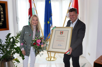Ein seltenes Bild: Uta Rojsek-Wiedergut vor der Linse – bei der Ehrung durch Bürgermeister Christian Scheider. Fotocredit: StadtKommunikation/Christian Rosenzopf