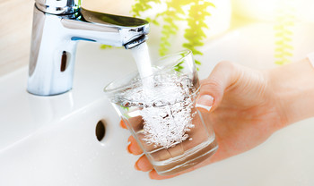 Wasserhahn fühlt Trinkglas