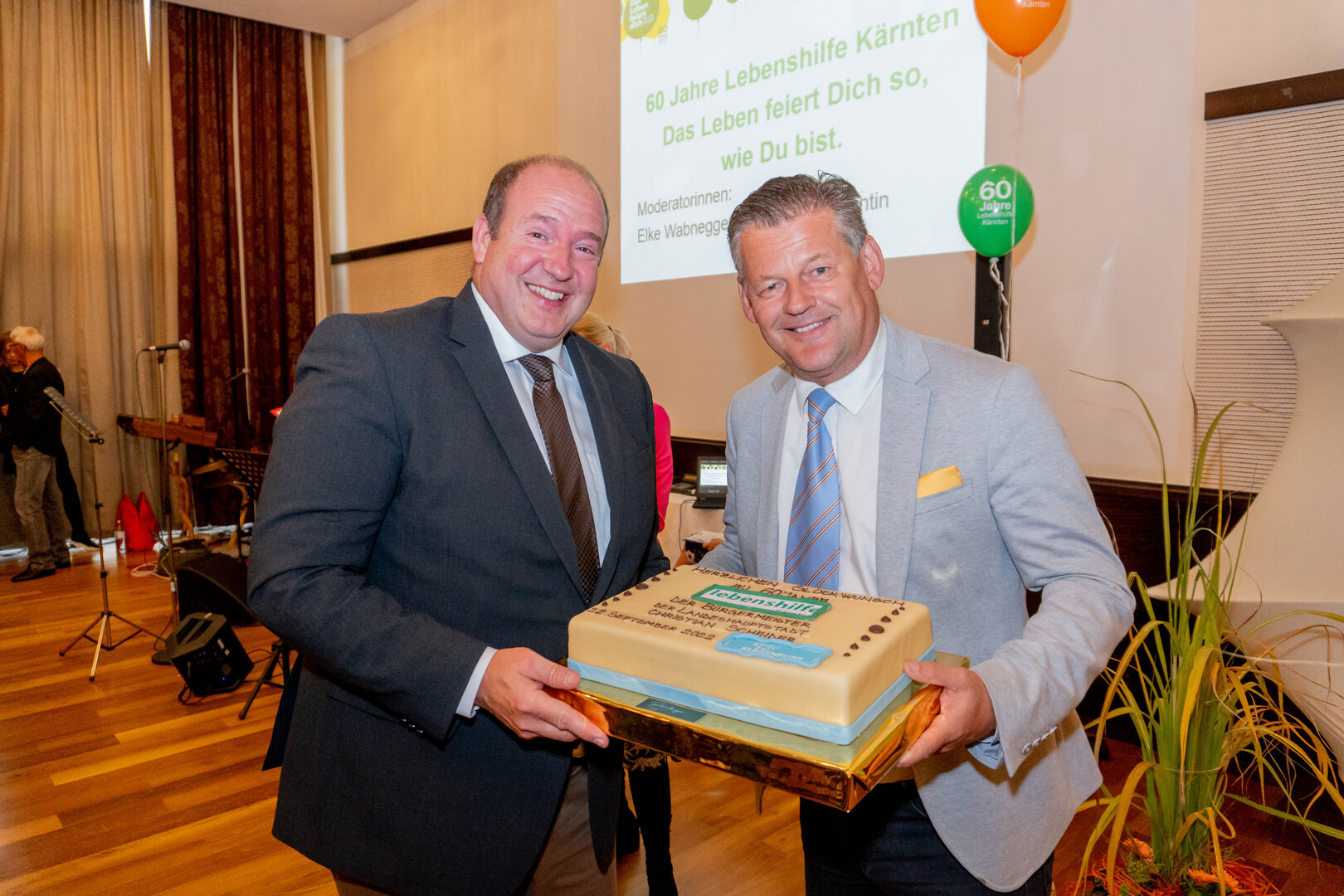 Bildtext: Bürgermeister Christian Scheider überreichte zum 60-jährigen Jubiläum feierlich eine Torte an den Präsident der Lebenshilfe Kärnten Mag. Anton Henckel-Donnersmark. Bild: StadtKommunikation/Wiedergut