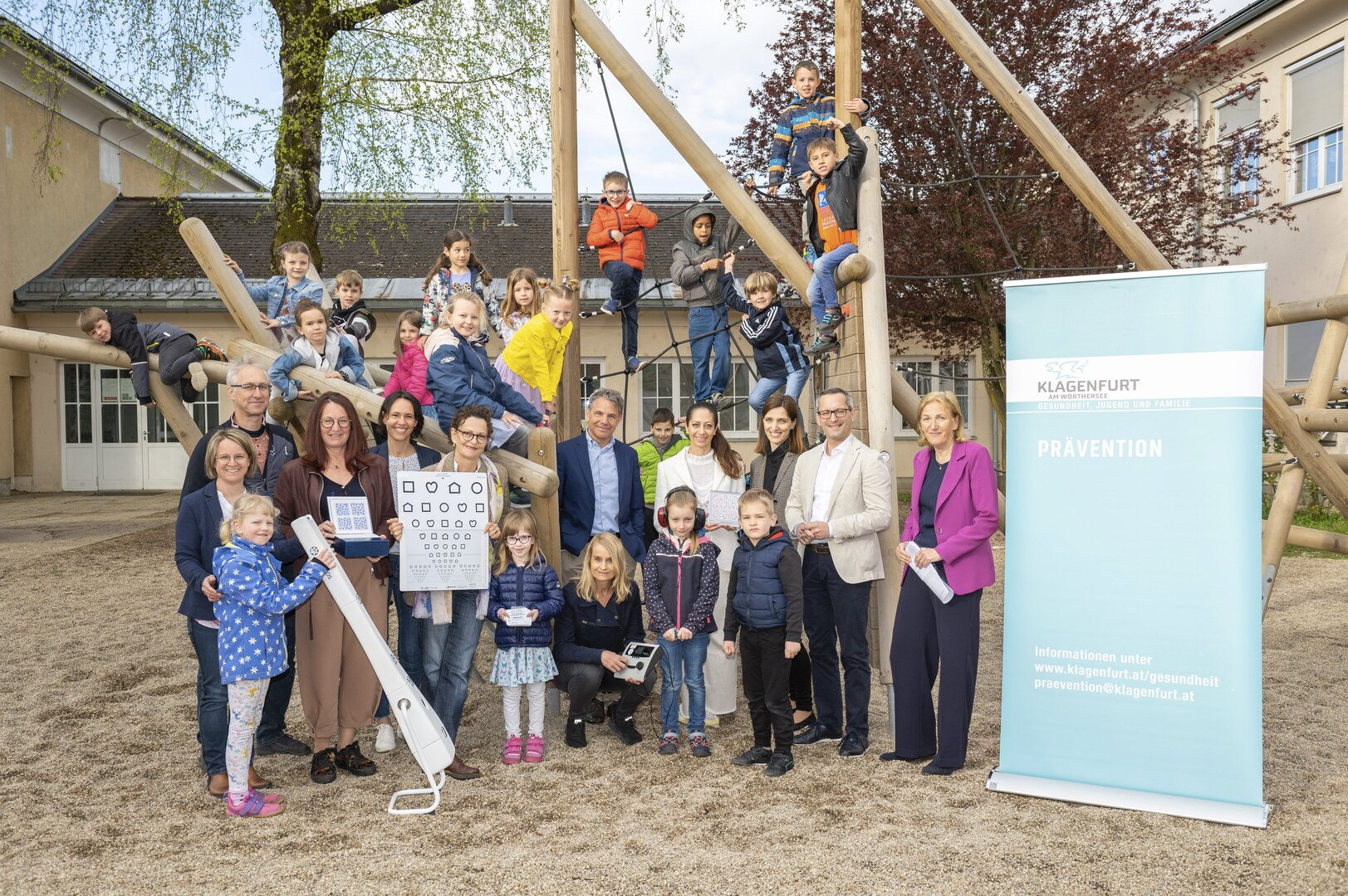 Die 1a und 1b Klasse der Volkschule 24 / Ljudska šola 24 mit Gesundheitsreferent Stadtrat Mag. Franz Petritz (rechts), den Verantwortlichen aus der Abteilung Gesundheit, Jugend und Familie, der Landesinnungsstelle der Gesundheitsberufe sowie Univ-Prof. Dr. Yosuf El-Shabrawi von der Abteilung für Augenheilkunde und Optometrie des Klinikums (mitte) und Schuldirektor Eduard Oraže (links). Foto: SK/Hude