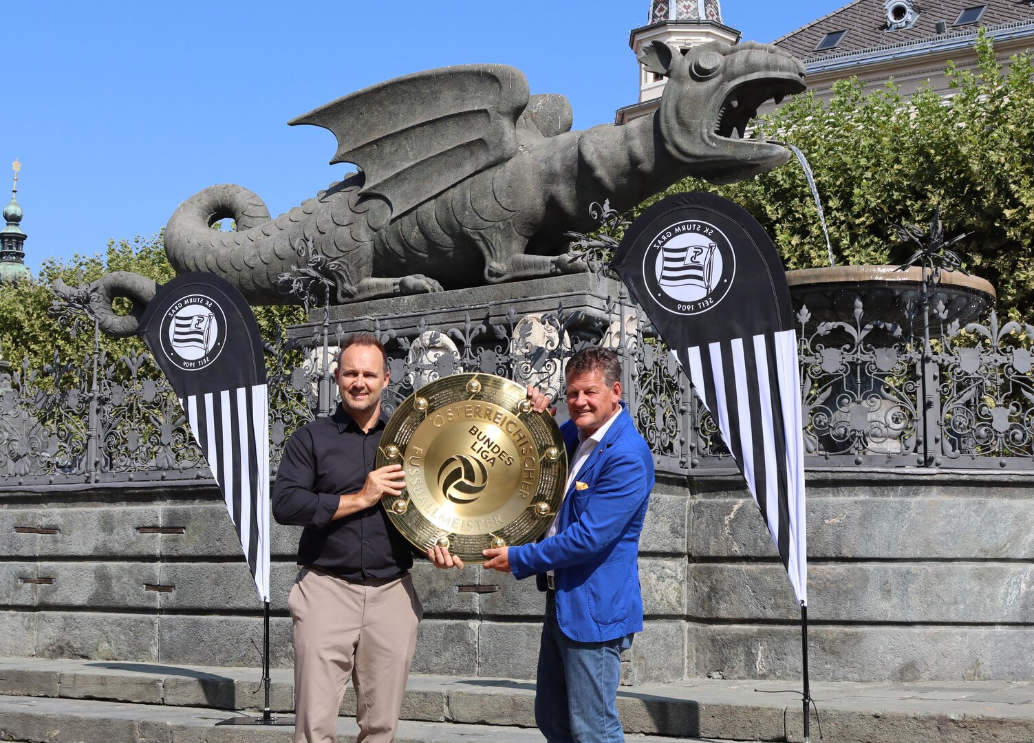 Bürgermeister Christian Scheider mit Mag. (FH) Thomas Tebbich, Geschäftsführer Wirtschaft des SK Sturm Graz, und dem Meisterteller am Neuen Platz in Klagenfurt. Foto: StadtKommunikation/Tilli