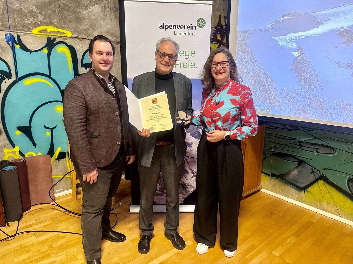 Sportreferentin Stadträtin DI Constance Mochar überreichte Franz Guggi das Silberne Sportehrenzeichen der Landeshauptstadt Klagenfurt im Rahmen einer Vorstandssitzung des Alpenvereins Klagenfurt. Mit am Foto: Daniel Uschounig, MBA MBA (1. Vorsitzender des Alpenvereins Klagenfurt) Foto: Büro Mochar