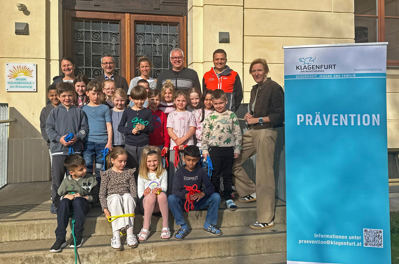 v.l. Mag. Christina Hasslinger (Präventionsstelle), Stadtrat Mag. Franz Petritz mit Klassenlehrerin Nicole Kurath, Schuldirektor Martin Dumpelnik, Sportkoordinator des Landes Kärnten Mag. Christoph Hölzl sowie Dr. Birgit Trattler (Leiterin der Abt. Gesundheit, Jugend und Familie) mit den Kindern der teilnehmenden 1a-Klasse. Foto: Büro StR. Petritz