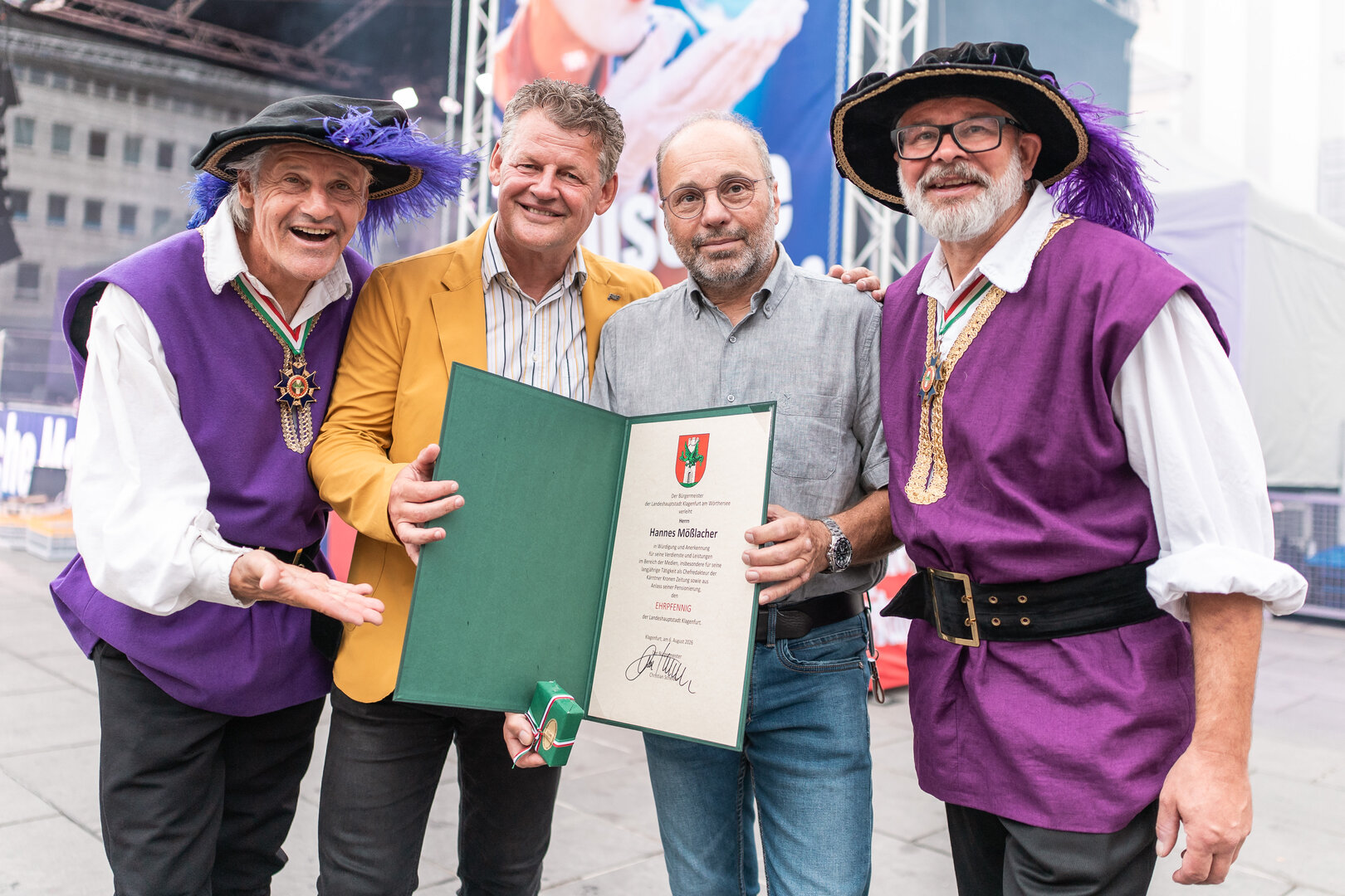 Bürgermeister Christian Scheider überreichte Hannes Mößlacher bei der Eröffnungsfeier des Altstadtzaubers den Ehrpfennig der Landeshauptstadt Klagenfurt, um ihn für seine Leistungen im journalistischen Bereich zu ehren. Foto: StadtKommunikation/Zangerle
