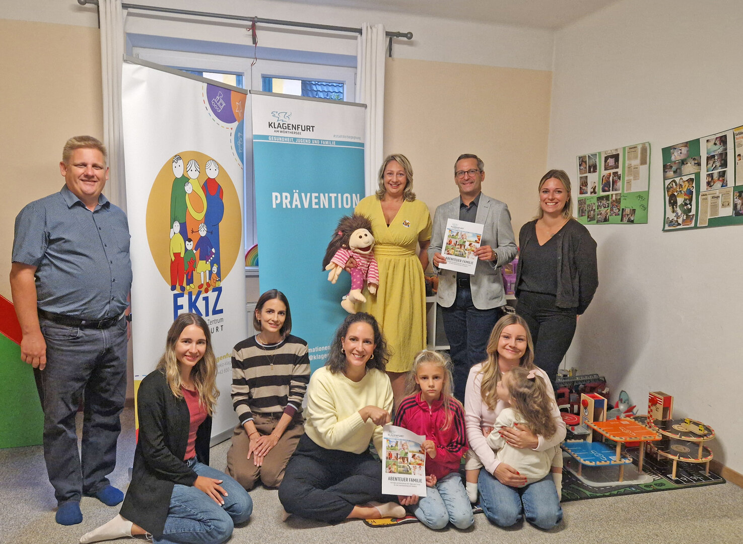 vl. Unten: Laura Mandl (Schuldnerberatung Kärnten), Corinna Sabin, MA (Praxis Querkopf), Mag. Barbara Schreier (Prävention) sowie v.l. stehend: Michael und Andrea Cechak-Pötscher (EkiZ), StR. Mag. Franz Petritz sowie Naomi Rieger-Mathews (Bärenstark mit Lissi) präsentieren das neue Abenteuer-Familie-Programm für Herbst 2026. Foto: SK/Glinik