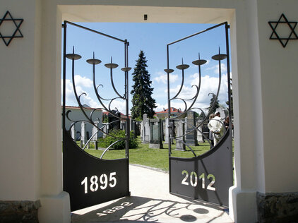 Das Tor zum israelitischen Friedhof mit den Jahreszahlen und einer Menora (siebenarmiger Leuchter) aus Schmiedeeisen.